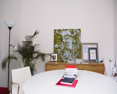 A small bright office room in Santiago with wooden furniture, books and healthy indoor green plants